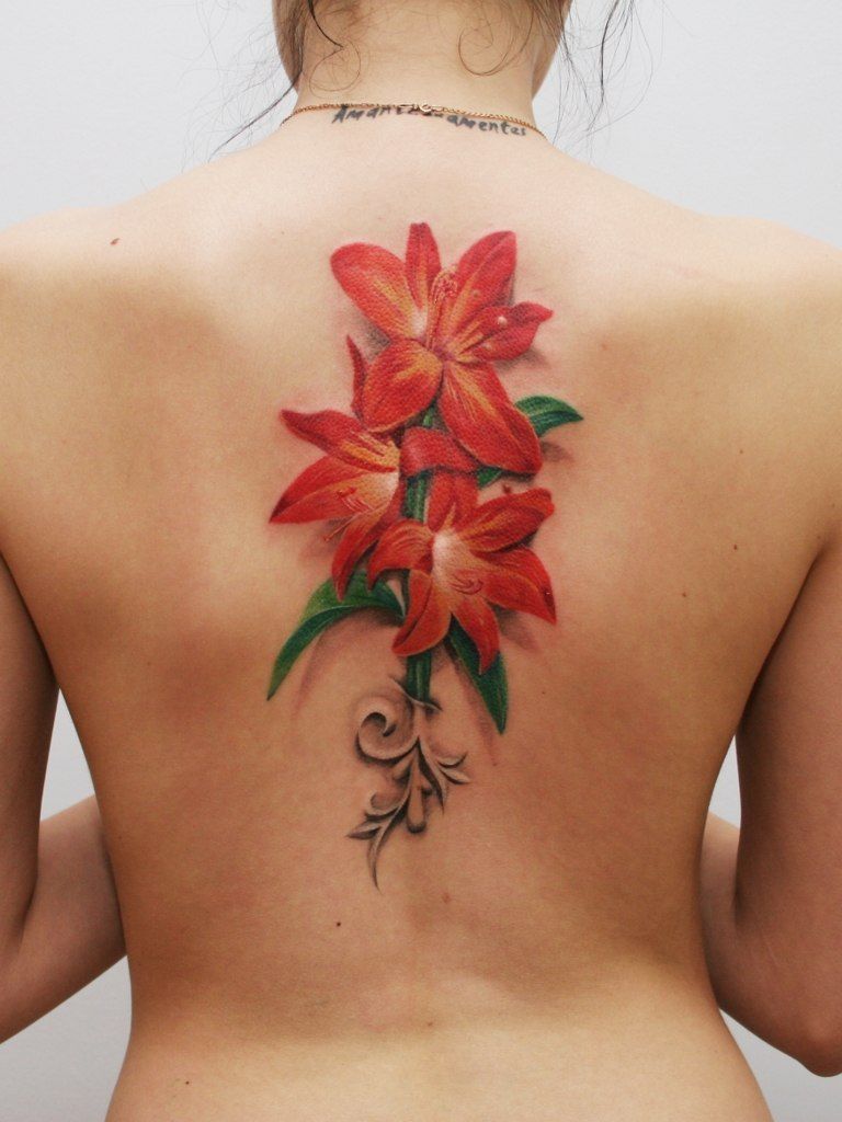 Colorful tattoo of a large lily on the back for women