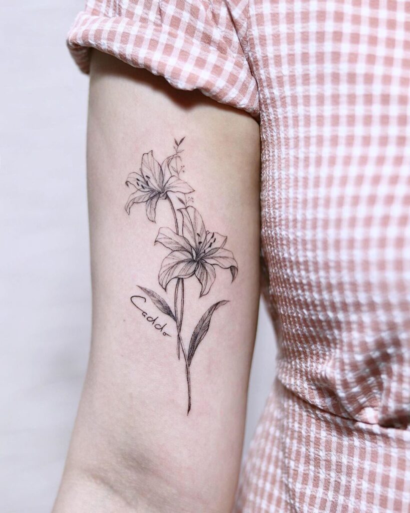 Lily tattoo with inscription on the shoulder for women