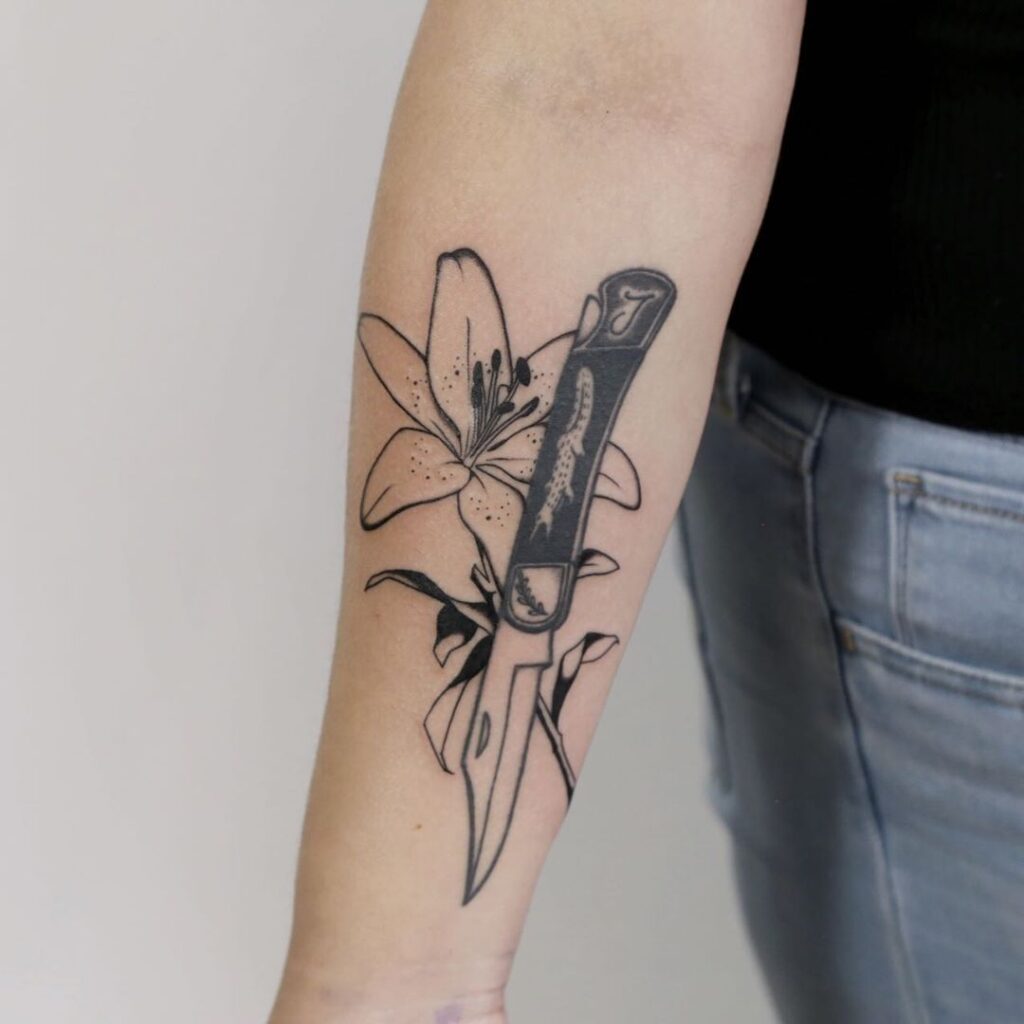 Lily and knife tattoo on the forearm for women