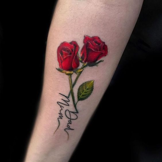 Colored rose tattoo with an inscription on the forearm for men