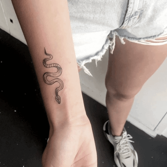 Tattoo of a small snake on the shoulder for women