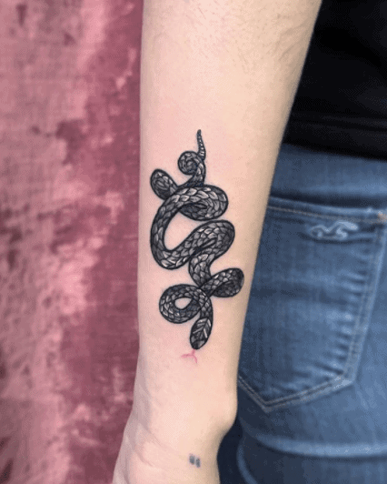 Tattoo of a small snake on the shoulder for women