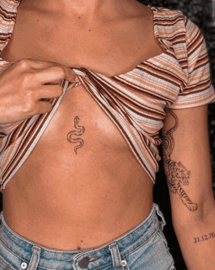 Tattoo of a small snake on the chest for women