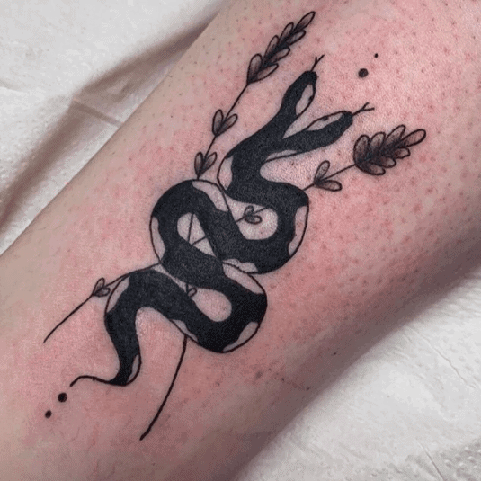 Tattoo of a small snake on the shin for women