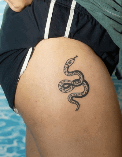 Tattoo of a small snake on the hip for women