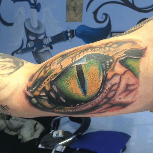 Tattoo of a colored snake eye on the shoulder for men