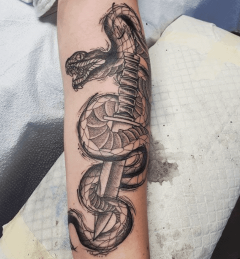 Snake and dagger tattoo on forearm for women