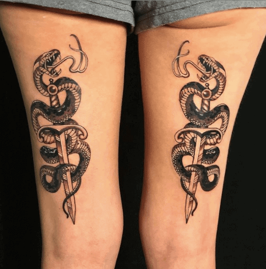 Tattoo of two snakes and daggers on the thigh for women