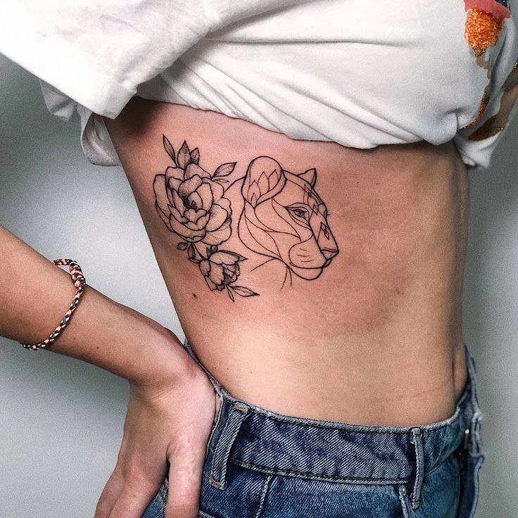 Tattoo of a lion with flowers on the side for women