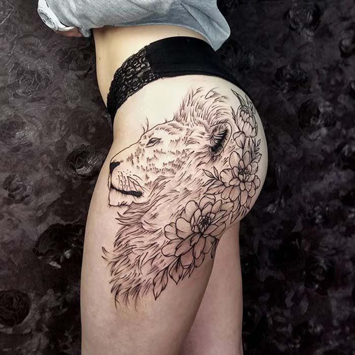 Tattoo of a lion with flowers on the hip for women