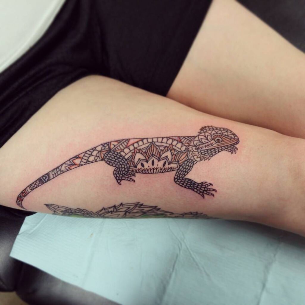 Tattoo of an iguana on the thigh for women