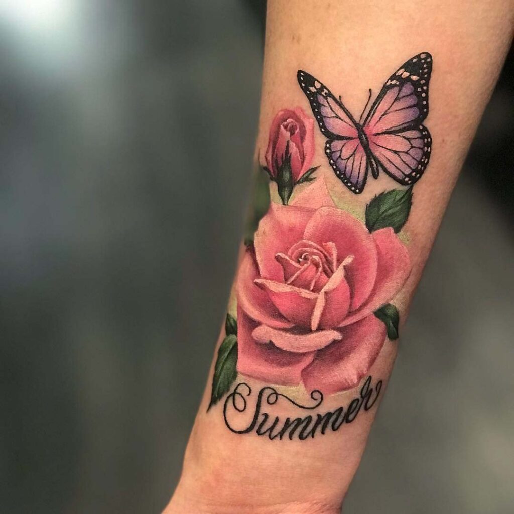 Colorful tattoo of a rose with a butterfly and an inscription on the forearm for women