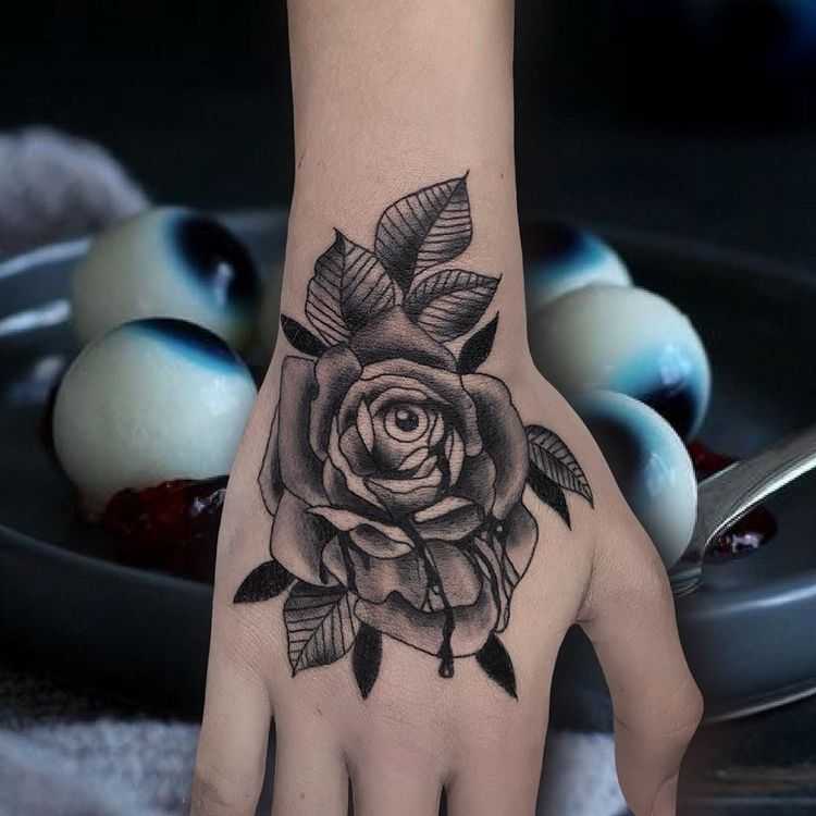 Tattoo of a rose with an eye on the brush for women