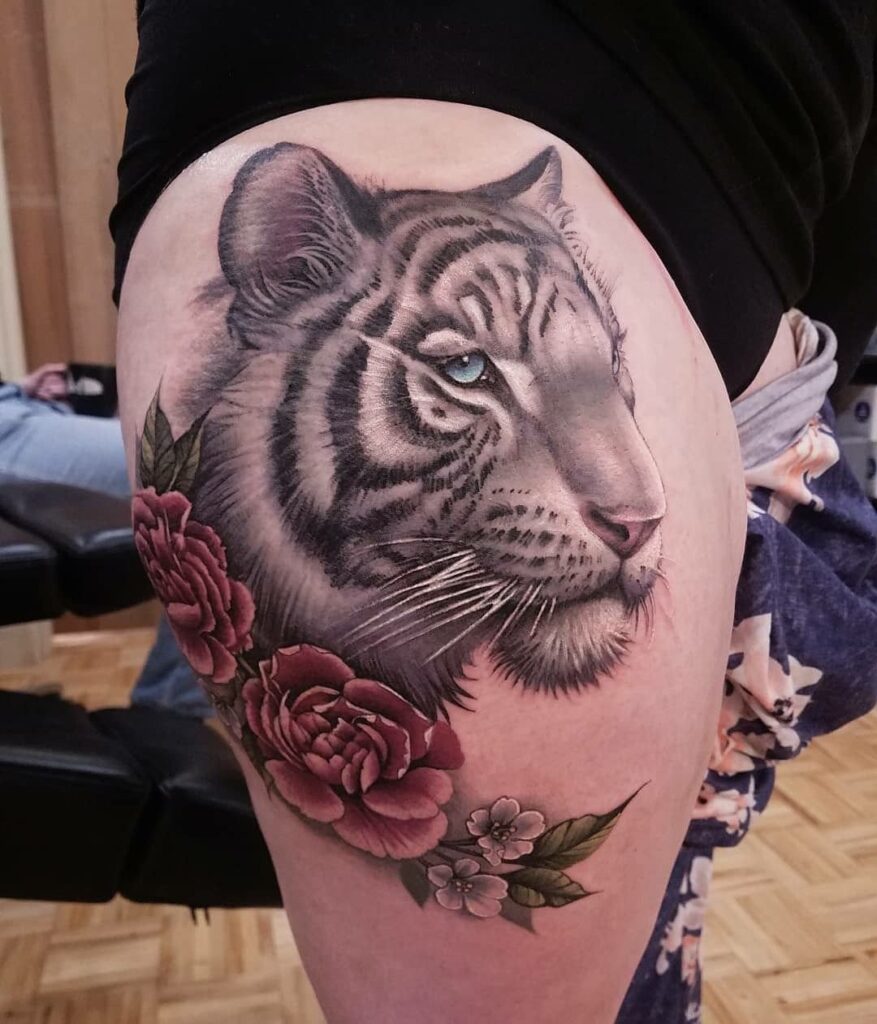 Tattoo of a tiger and flowers on the hip for women