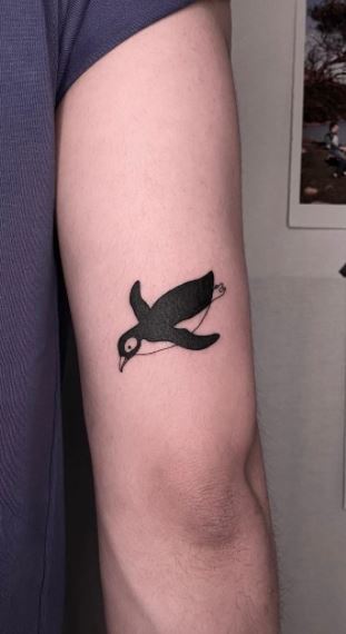 Tattoo of a penguin on the shoulder for men