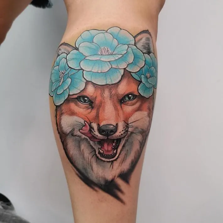 Tattoo of a fox with flowers on a calf for women