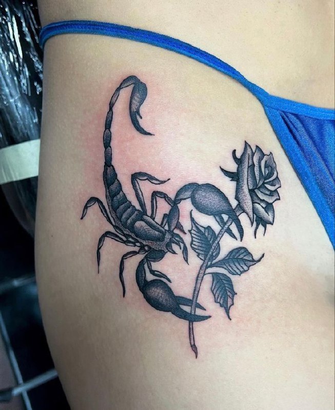 Tattoo of a scorpion with a rose on her thigh for women