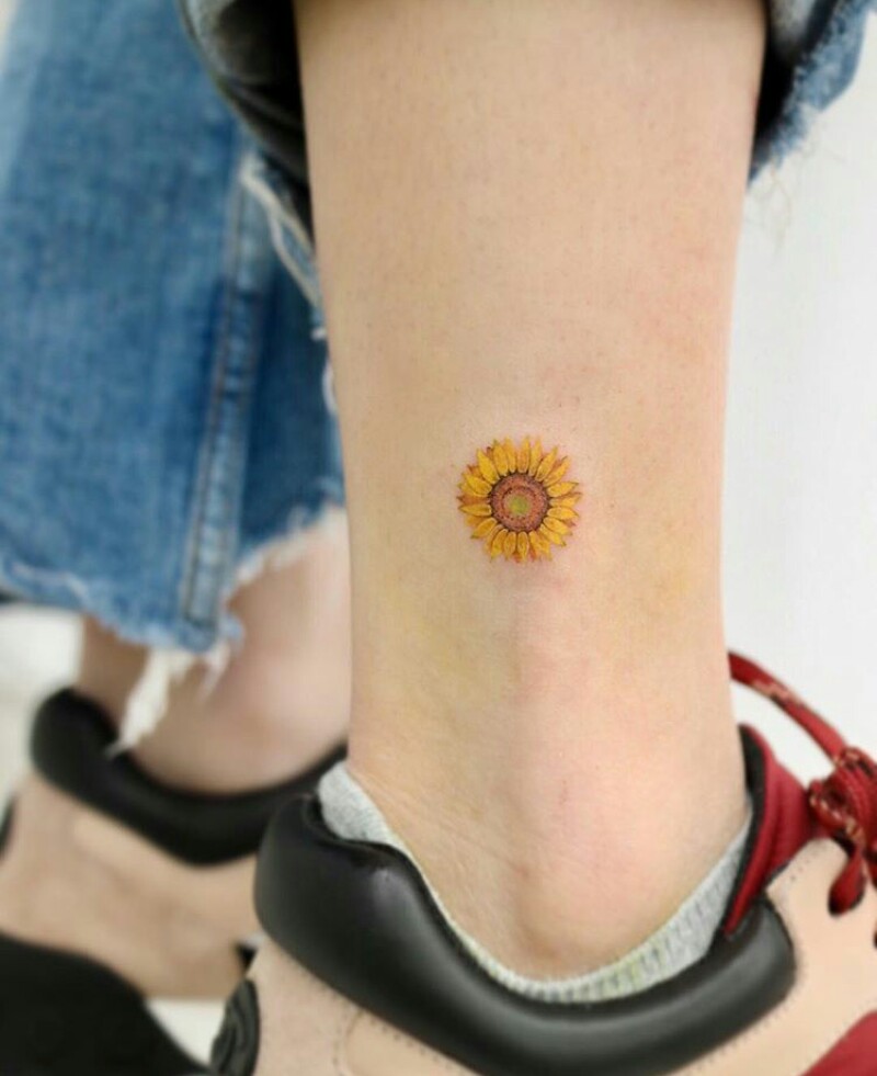 Small sunflower tattoo on the shin for women