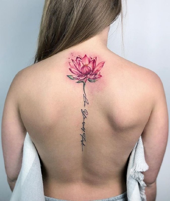 Colored lotus tattoo with inscription on the spine for women