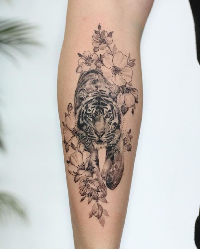 Tattoo of a tiger with flowers on a calf for women