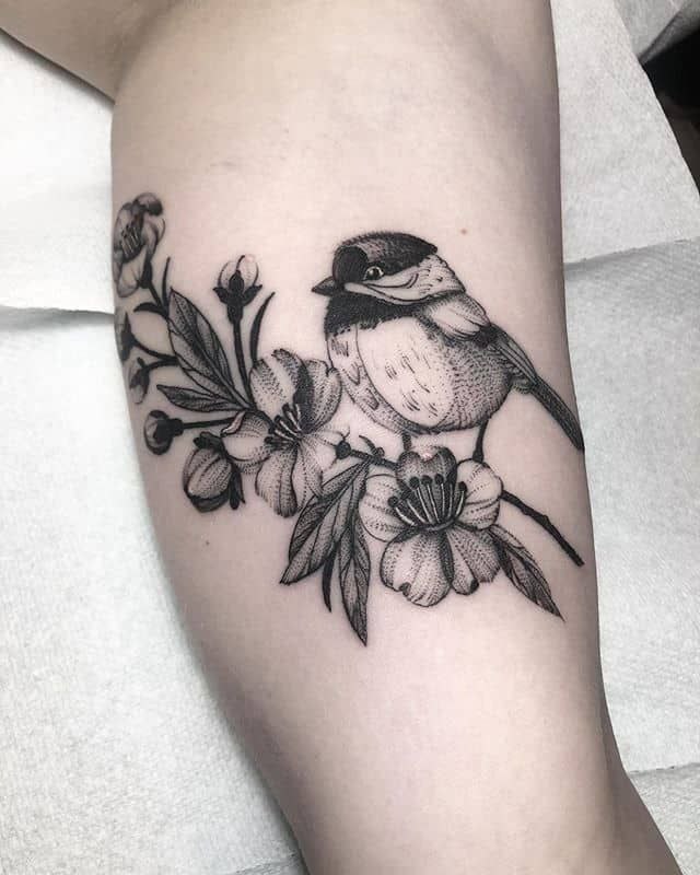 Large tattoo of a sparrow with flowers on the shin for men