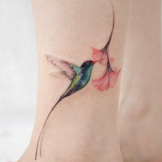 Colored hummingbird and flower tattoo on the shin for women