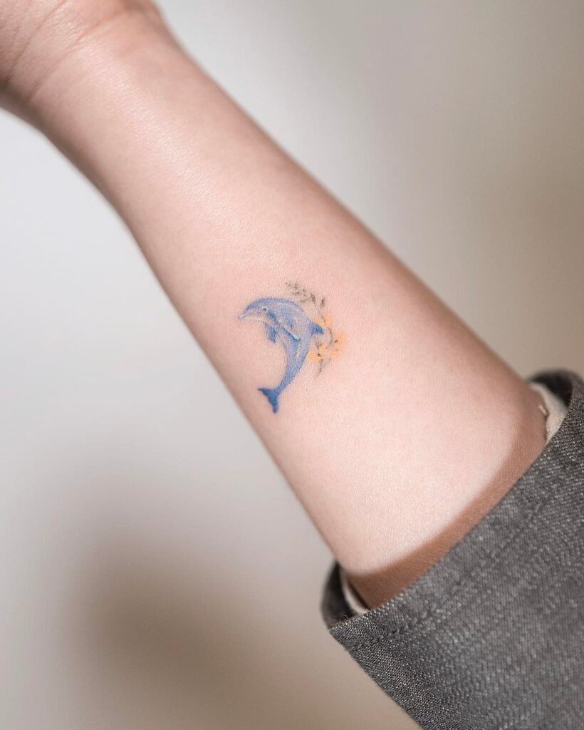 A small dolphin tattoo on the forearm for women