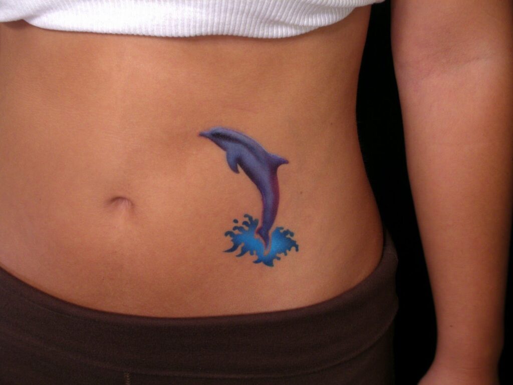 Colorful dolphin tattoo on the belly for women