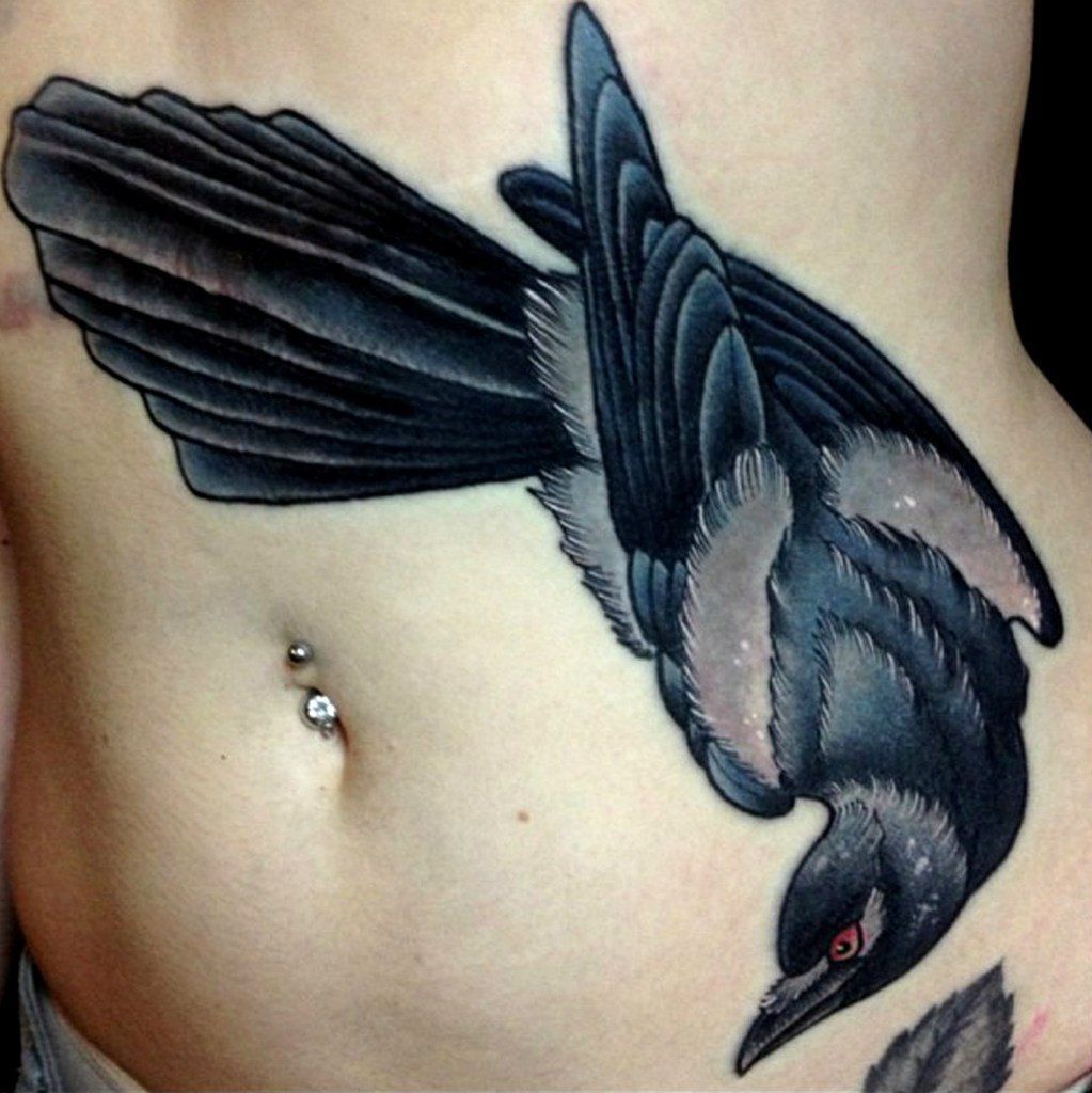 Color tattoo of a raven on the stomach for women