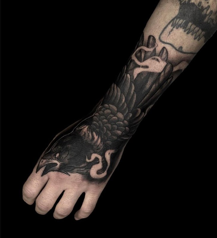 Large tattoo of a raven on the forearm for men