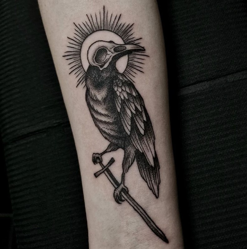 Tattoo of a raven with a dagger on the forearm for men