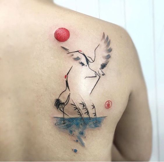 Colorful tattoo of two cranes on the shoulder blade for men