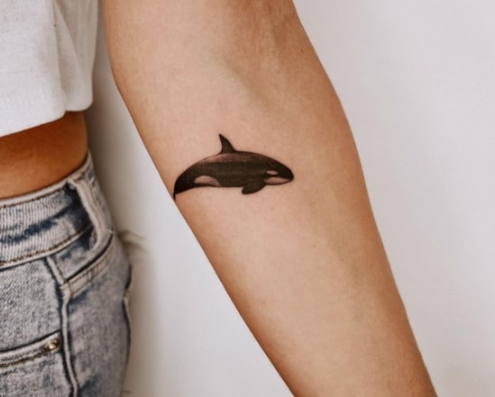 A small orca tattoo on the forearm for women