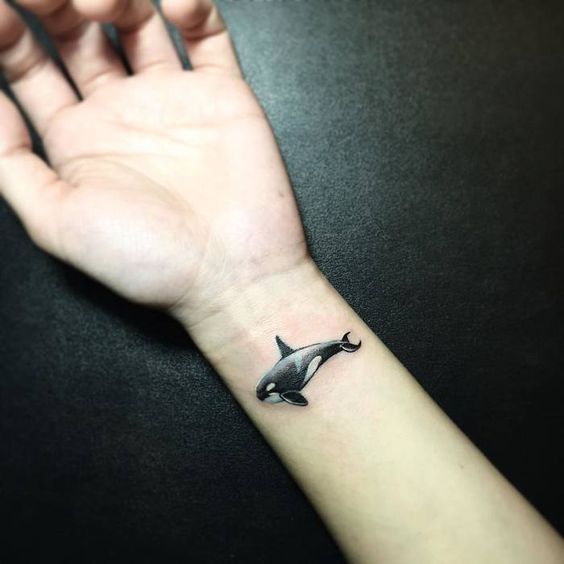 A small orca tattoo on the forearm for women