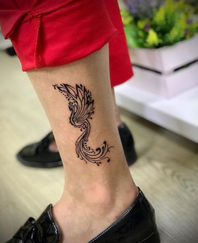 Small tattoo of a firebird on the shin for wome