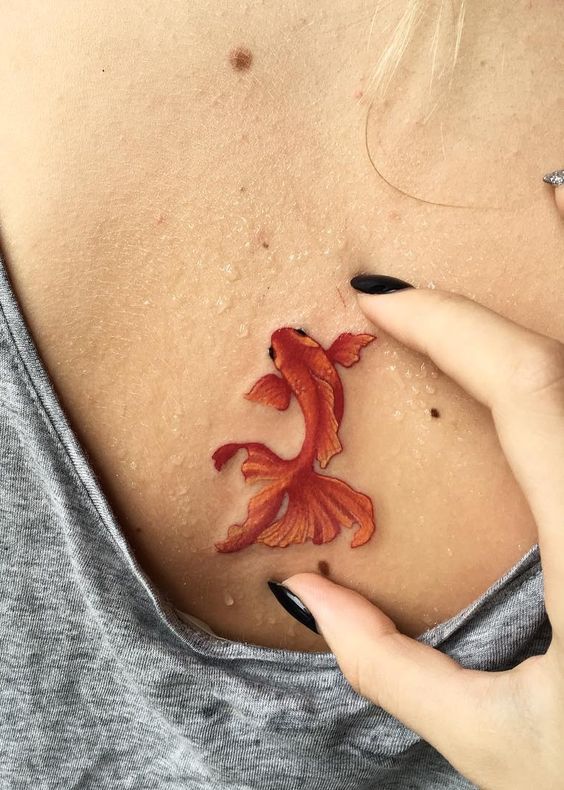 Colorful goldfish tattoo on the back for women