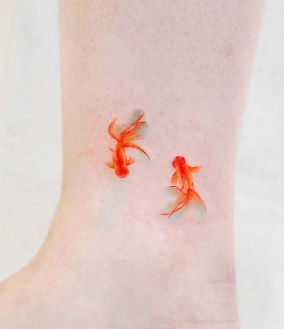 Small tattoo of two goldfish on the shin for women