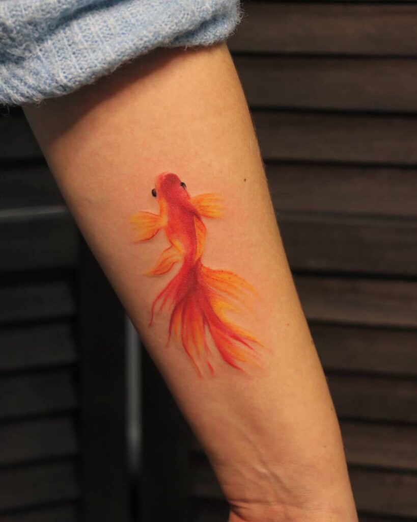 Colored goldfish tattoo on the forearm for women