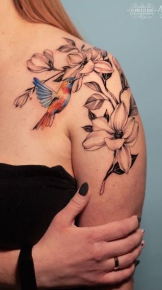 Color tattoo of a hummingbird with flowers on the shoulder for women