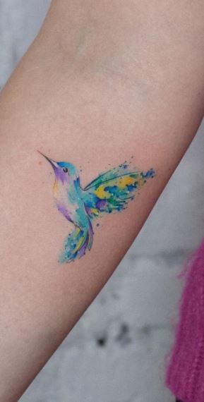 Colored hummingbird tattoo on the forearm for women