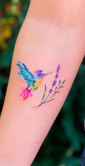 Colored hummingbird tattoo with a flower on the forearm for women