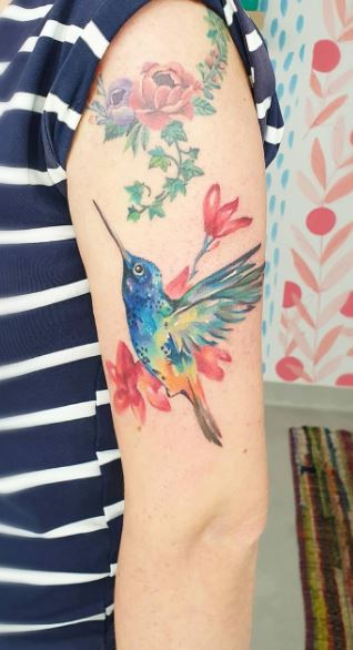 Large hummingbird tattoo with flowers on the shoulder for women