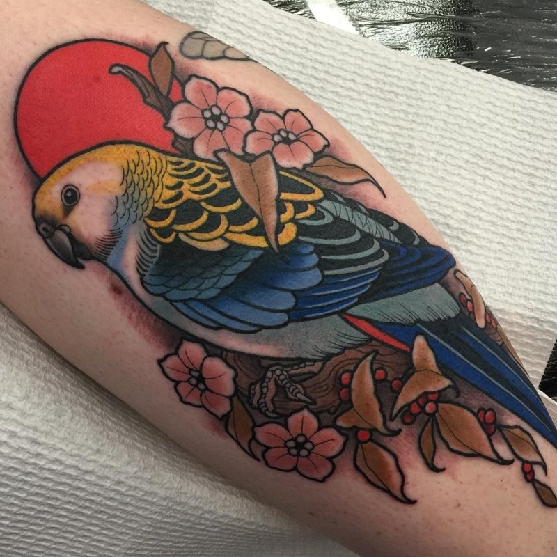 Large parrot and flower tattoo on the leg for women