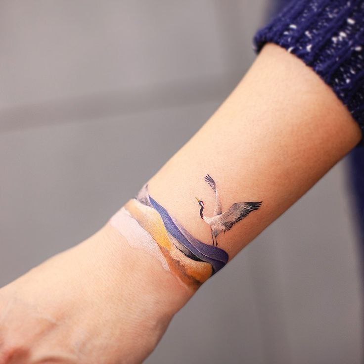 Colorful stork tattoo on the arm for women