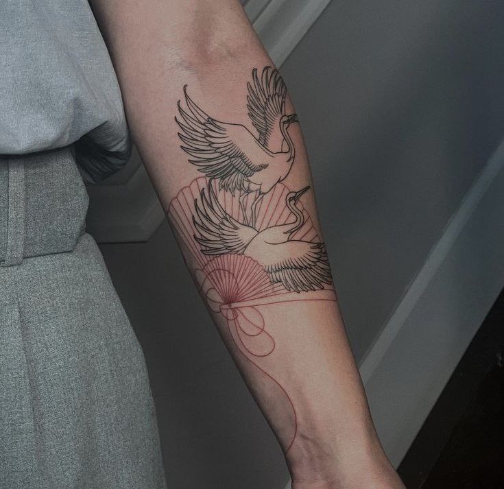 Tattoo of two storks on the forearm for women