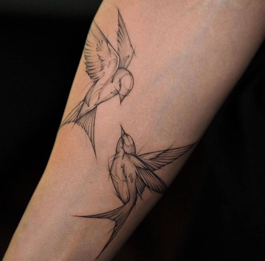 Large tattoo of two swallows on the forearm for men