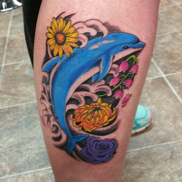 Colored tattoo of a dolphin with flowers on the shin for men