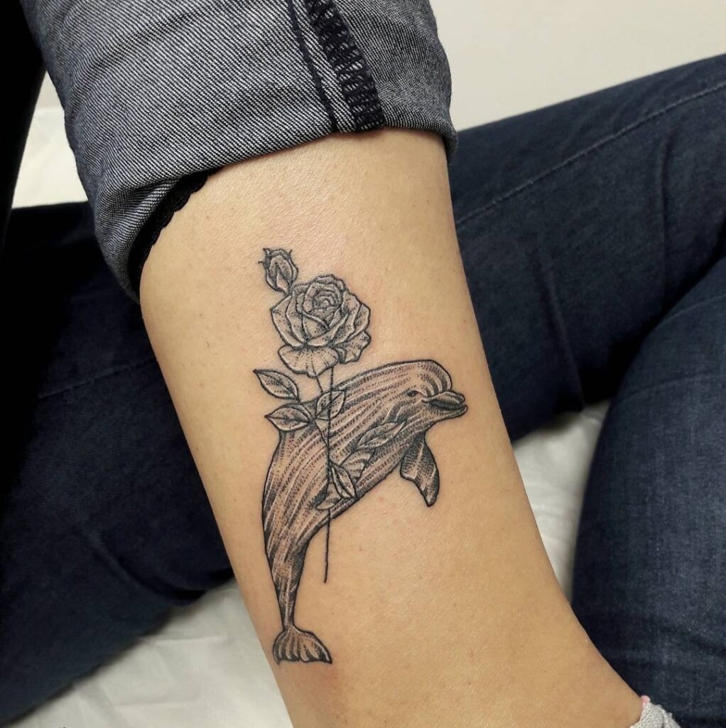 Dolphin tattoo with a rose on her shin for women