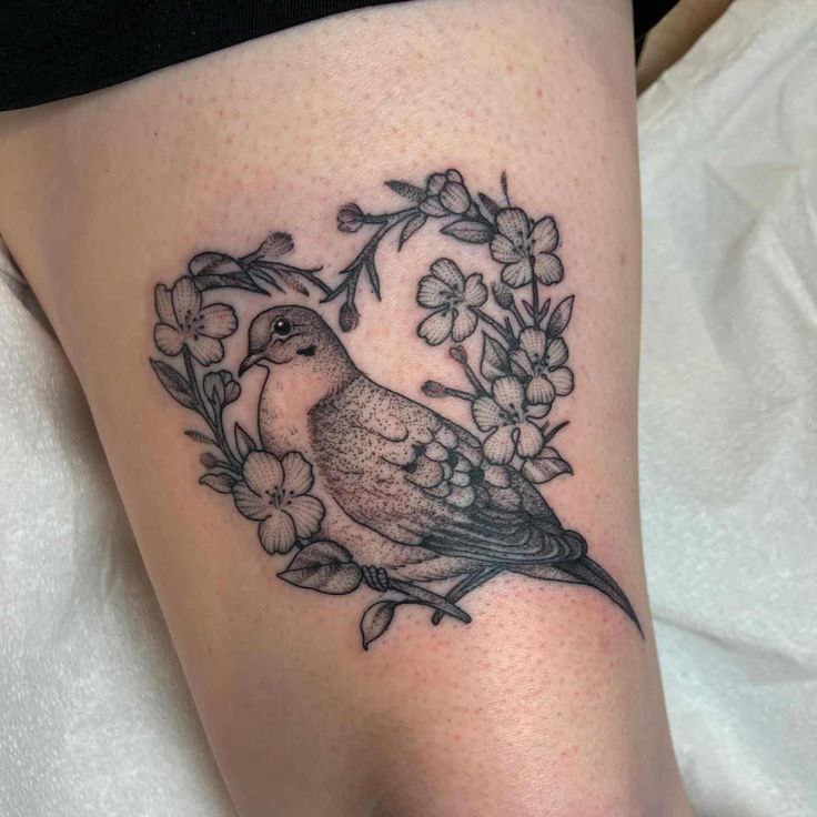 Tattoo of a dove with flowers on the hip for women