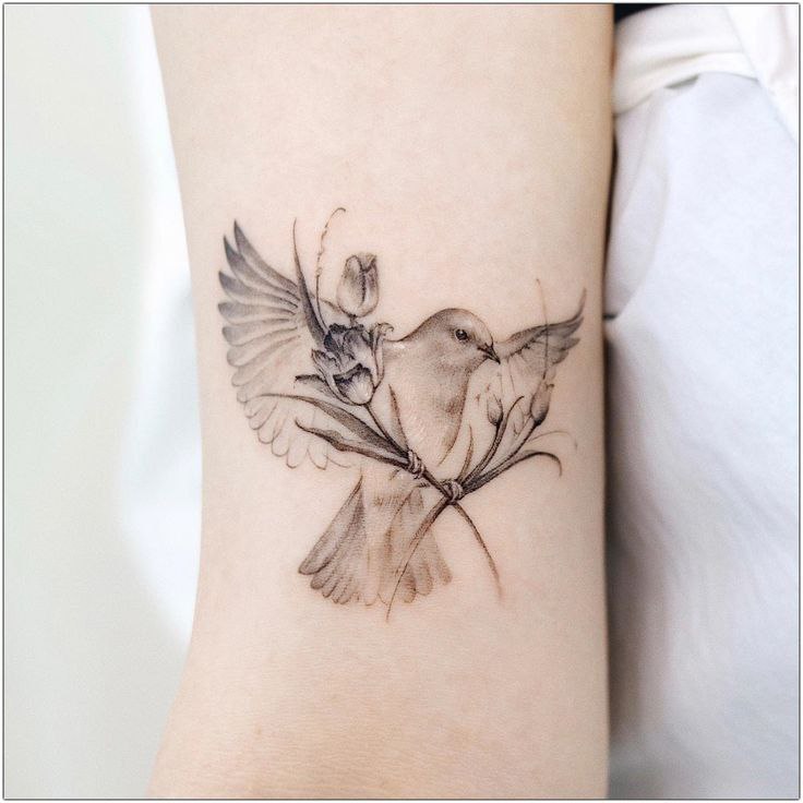 Tattoo of a dove and flowers on the shoulder for women